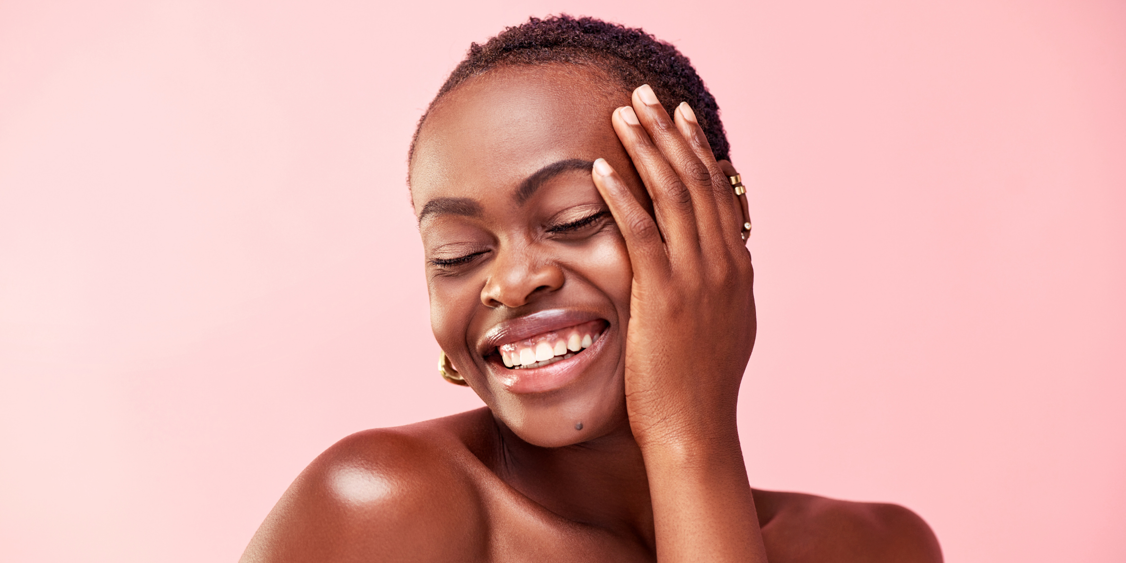 beautiful woman touching her skin and smiling with her eyes closed